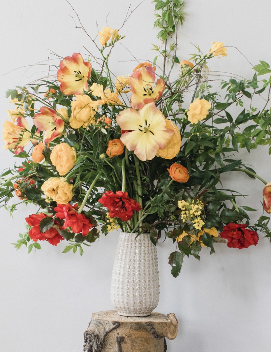 organic yellow and red flower arrangement mixed in with greenery
