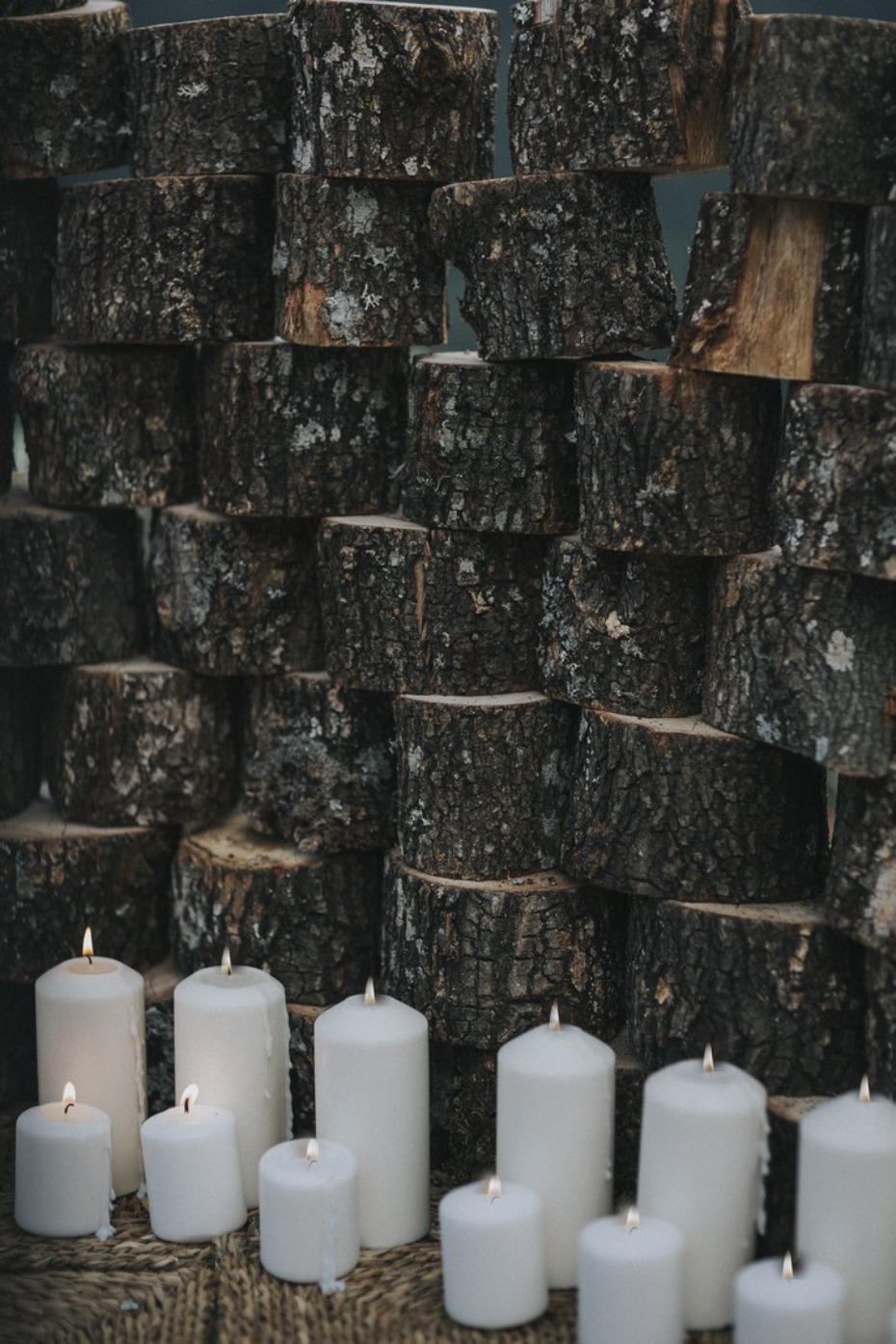 pillar candles and stacked wooden stumps wedding backdrop