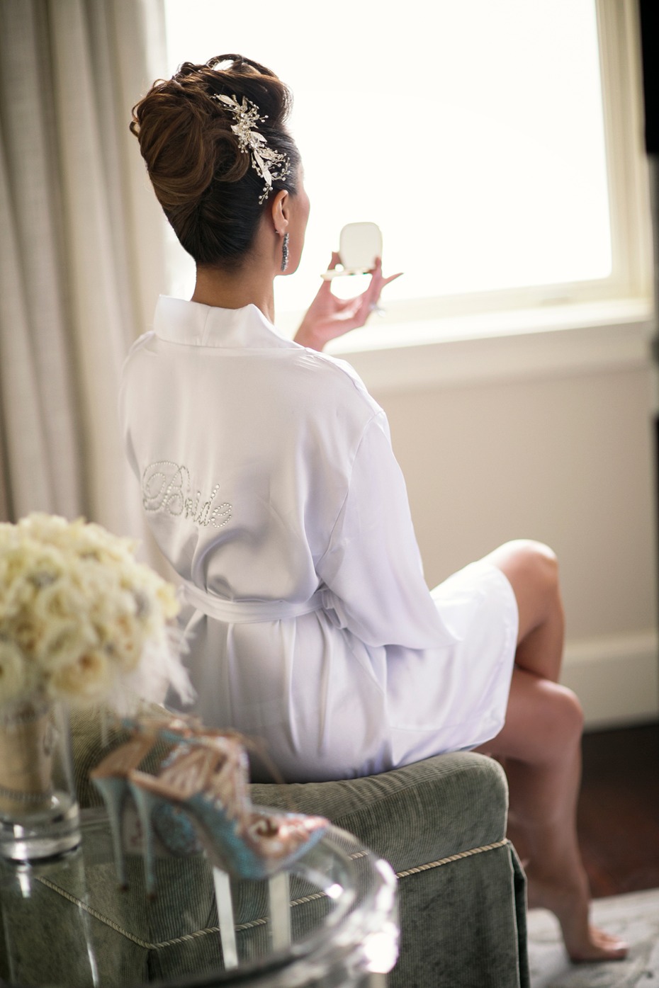 Bride in robe admiring herself with shoes nearby on her special day