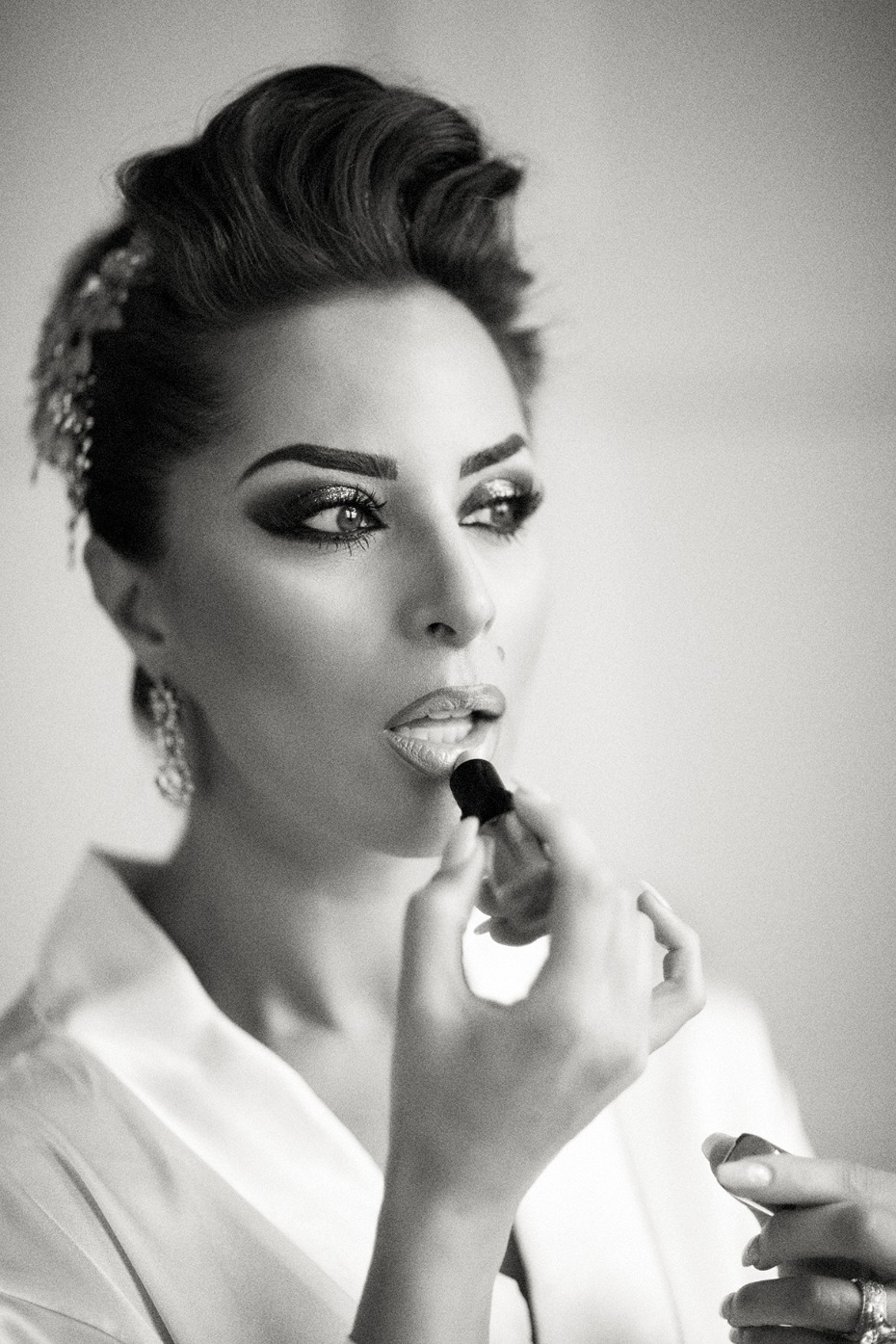 Elegant woman applying lipstick getting ready to go out