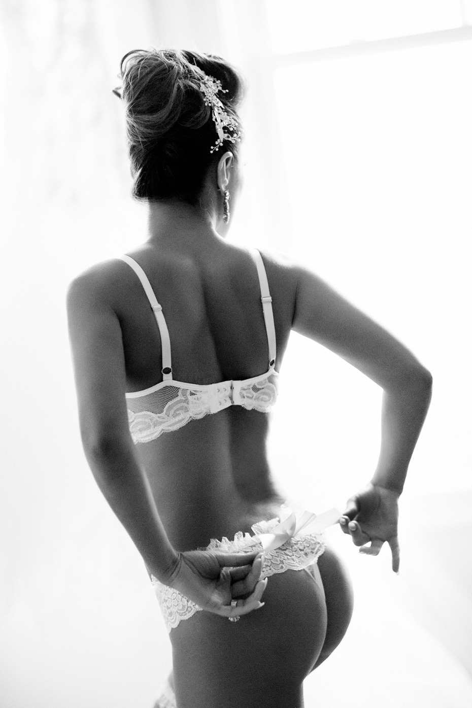 Bride in lingerie adjusts her lace thong in soft black and white