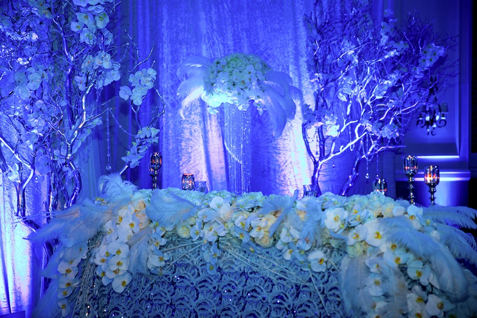 dramatic blue up lighting give this glamorous white wedding table an icy winter vibe