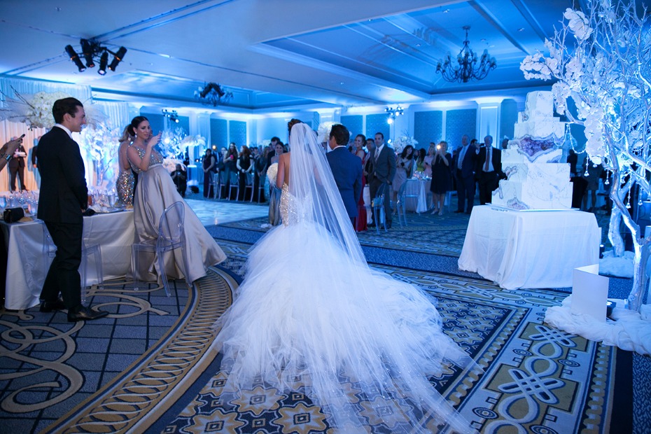 Bride walking down the aisle at a glamorous, blue-lit wedding