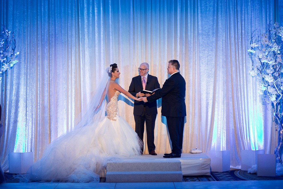 Bride and groom holding hands at a glamorous wedding ceremony