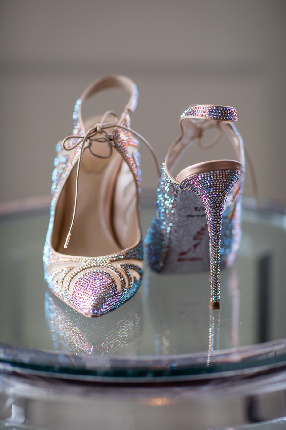 Sparkling jeweled wedding heels on a reflective glass surface