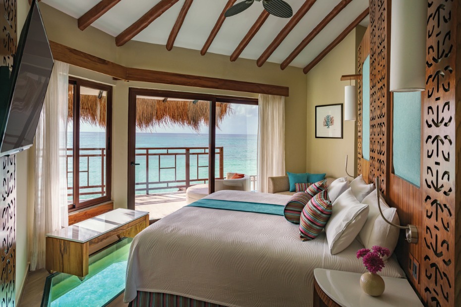 king bed  with glass floors and sweeping ocean views at the Palafitos