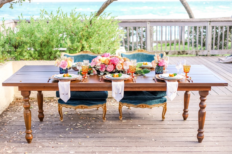 Elegant outdoor dining table set with ocean view and floral decor