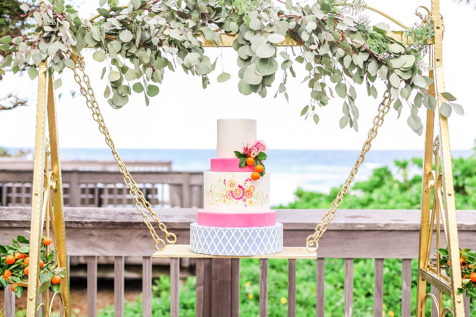Elegant wedding cake on a swing with ocean view and greenery