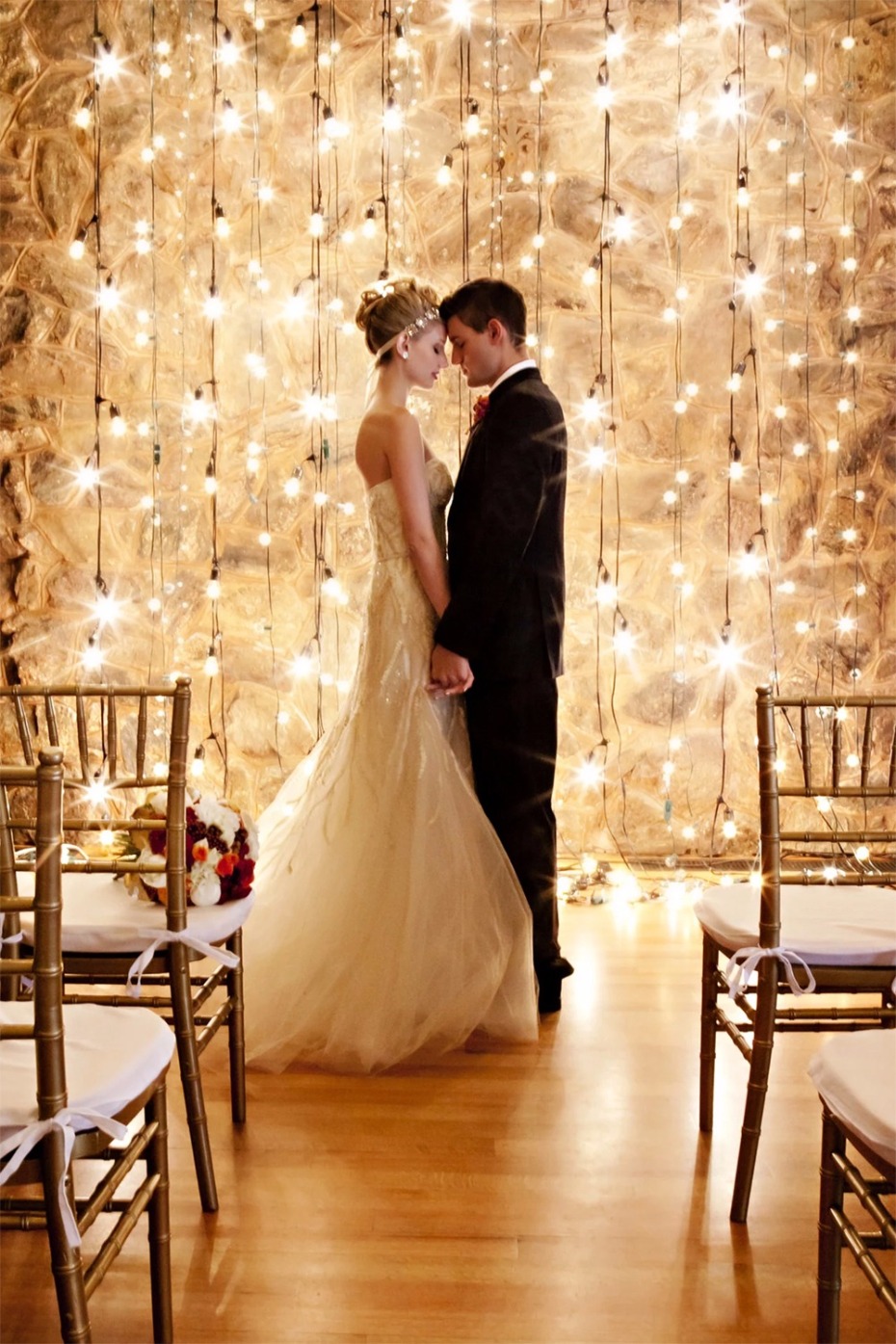 Bride and groom embrace under string lights at wedding