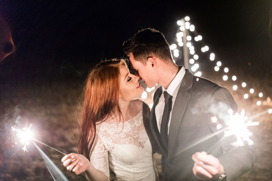 Newlyweds share a kiss with sparklers at their wedding