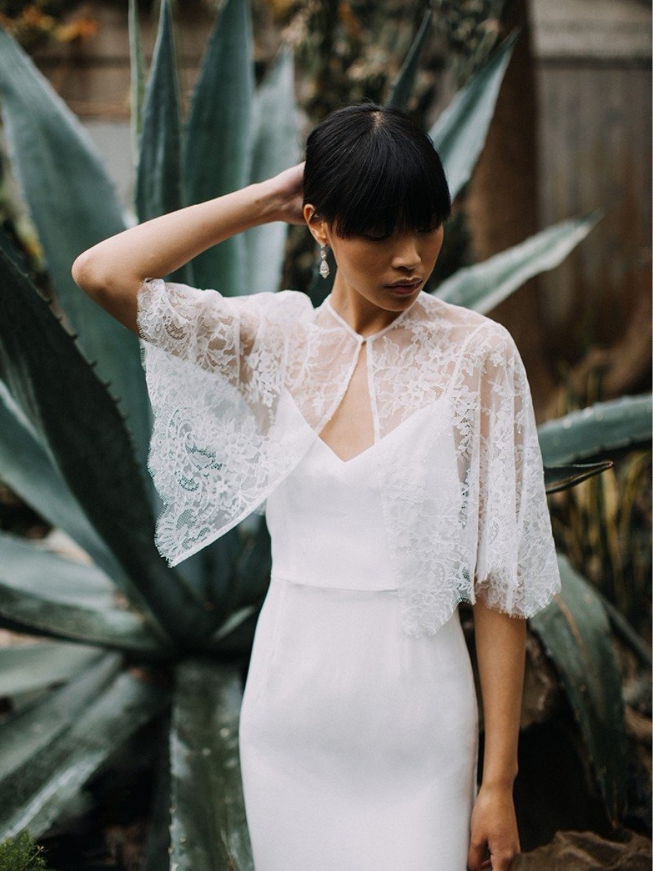 Elegant bride in white dress and lace cape posing beautifully