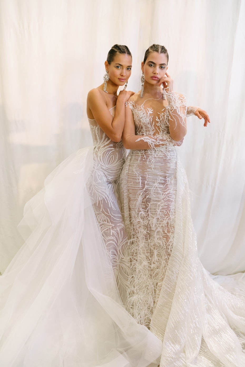 Two models wear exquisite sheer white wedding gowns