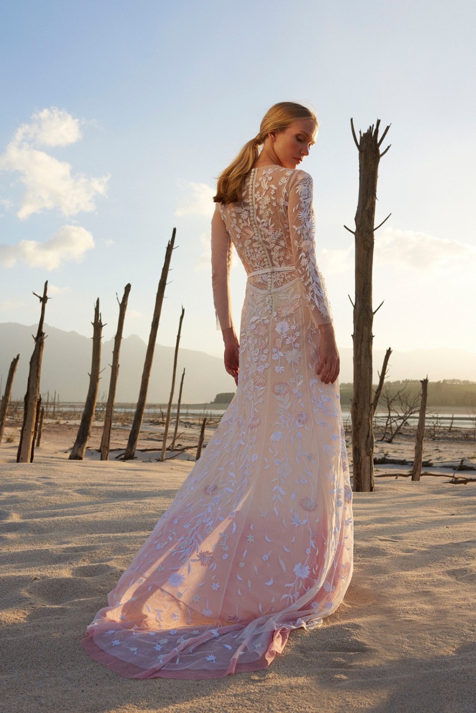Woman in floral long sleeved wedding dress on beach