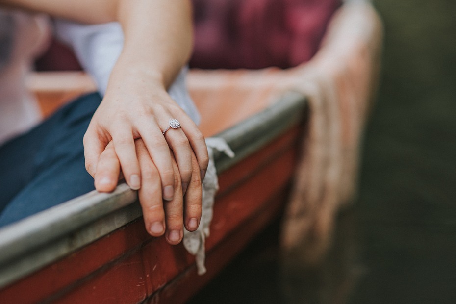 Close up of couple holding hands with engagement ring in boat