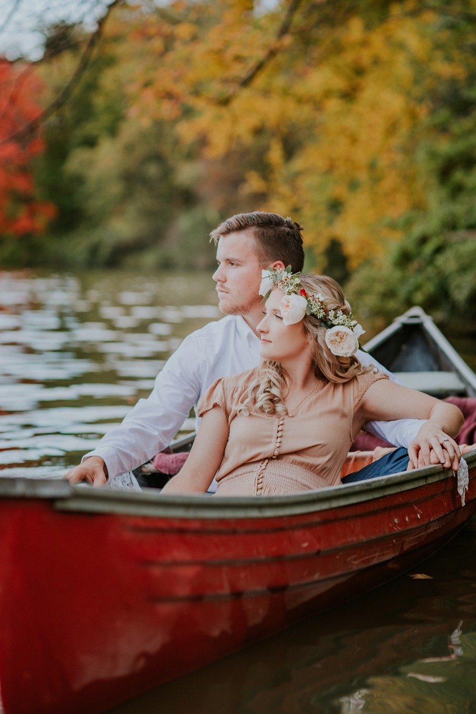 Romantic couple in a red canoe on a lake in autumn