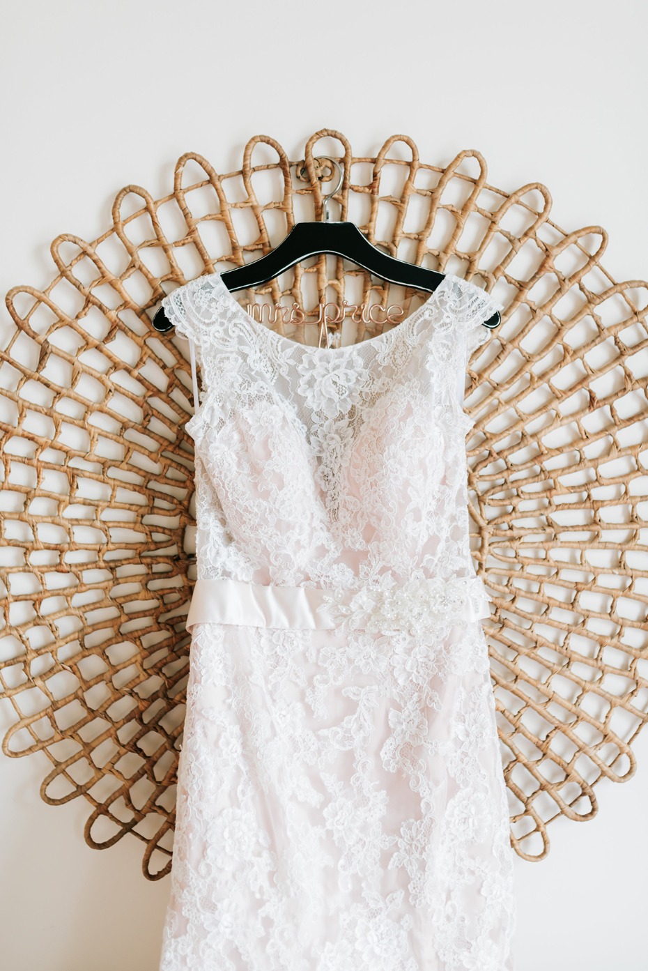 Lace wedding dress hanging on a woven wall decoration