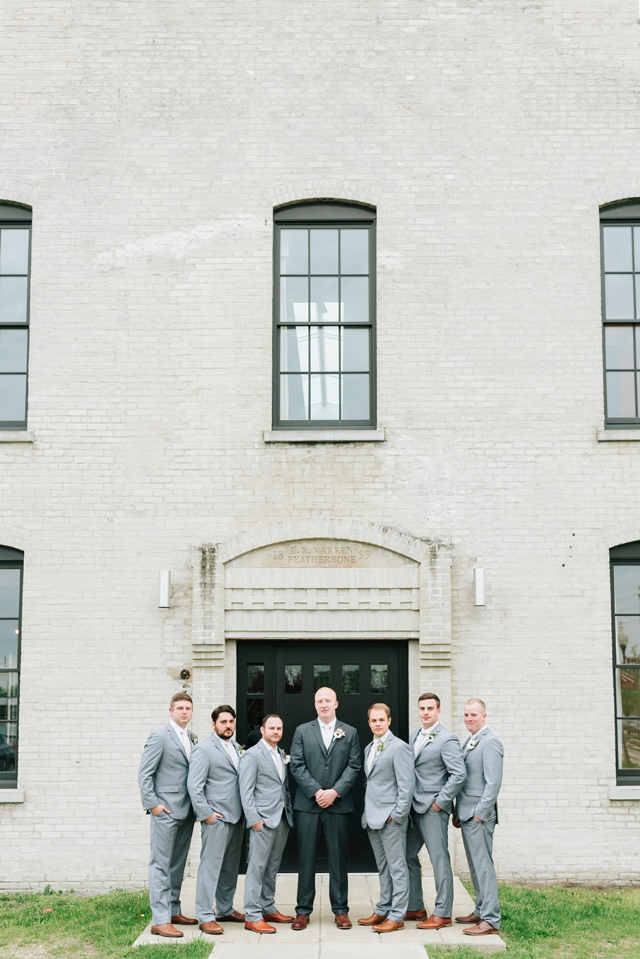 Groom and groomsmen in gray suits before wedding venue