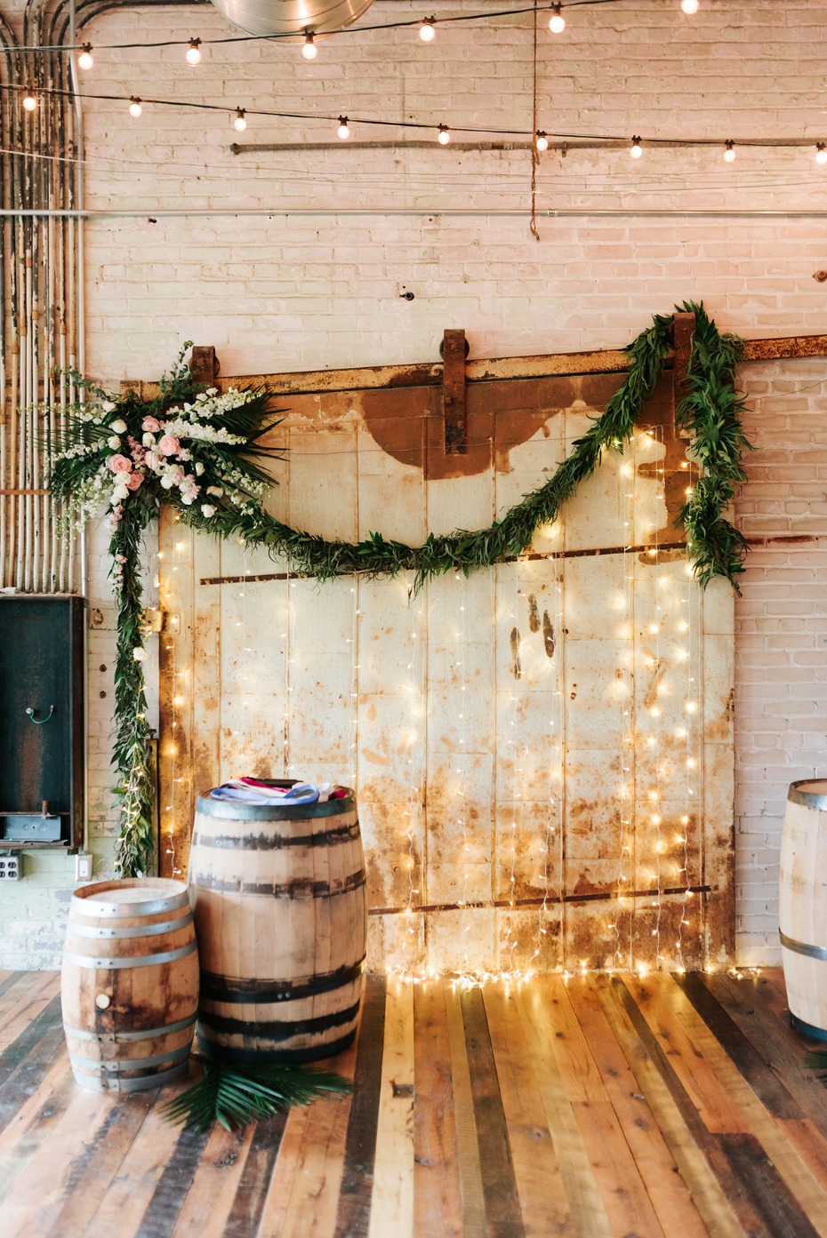 Rustic barn door backdrop with barrels and greenery decor