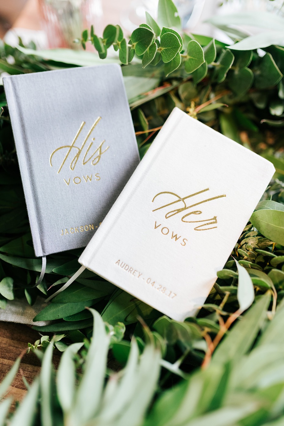 His and Her vow books surrounded by greenery detail