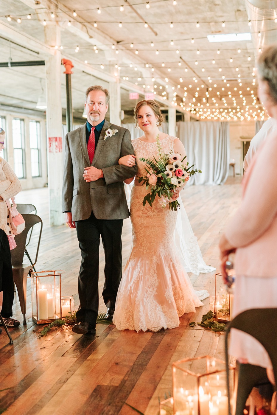 Bride escorted by her father at indoor wedding venue