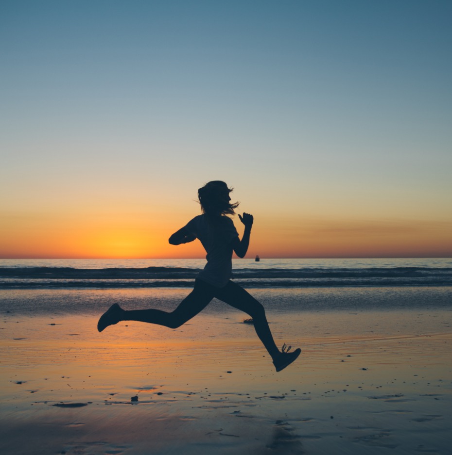 Woman running on beach at sunset
