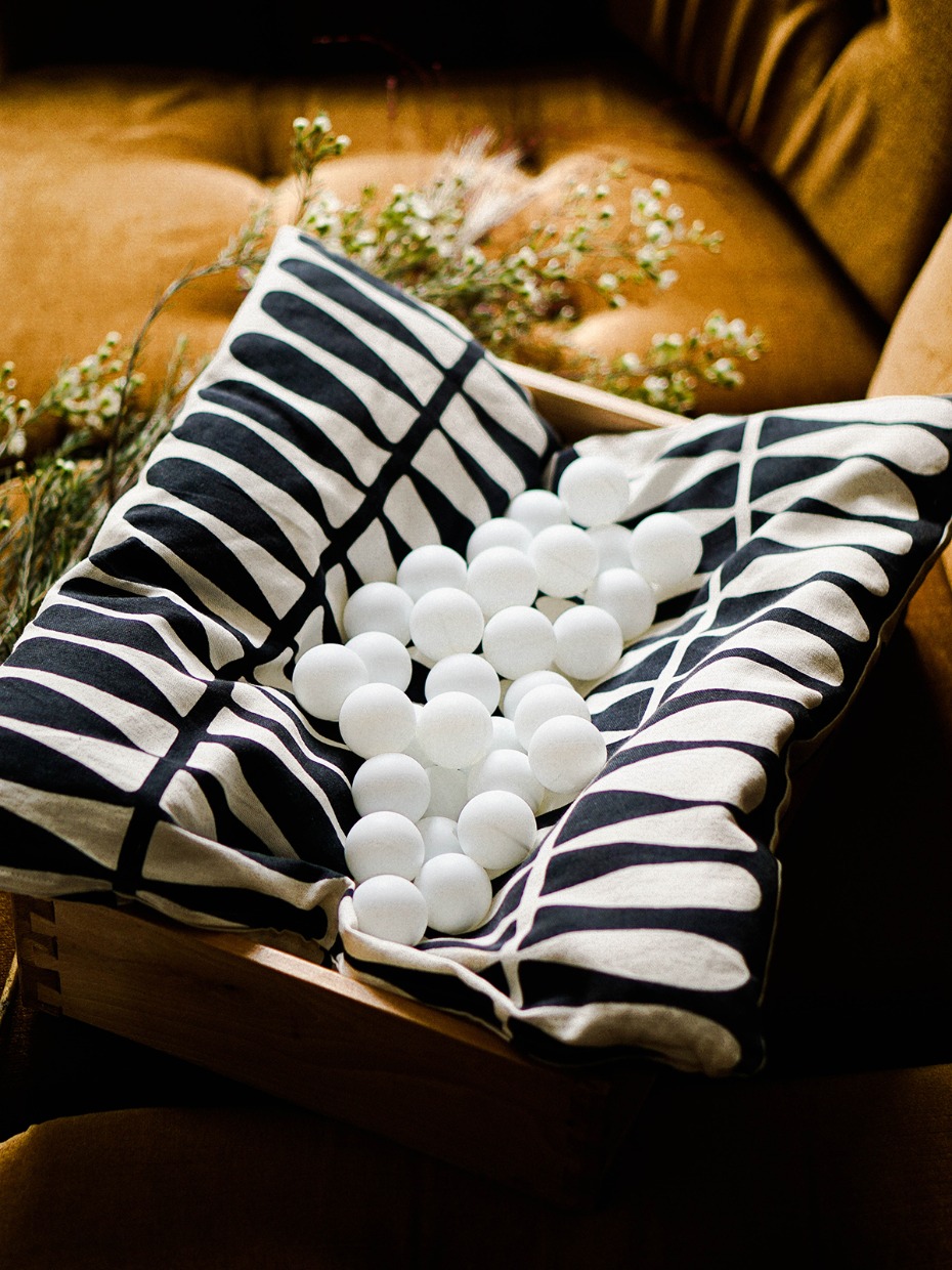 White balls in a patterned pillow in a rustic wooden box