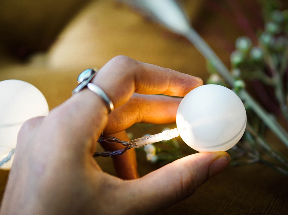 Hand holding a glowing spherical fairy light with rings