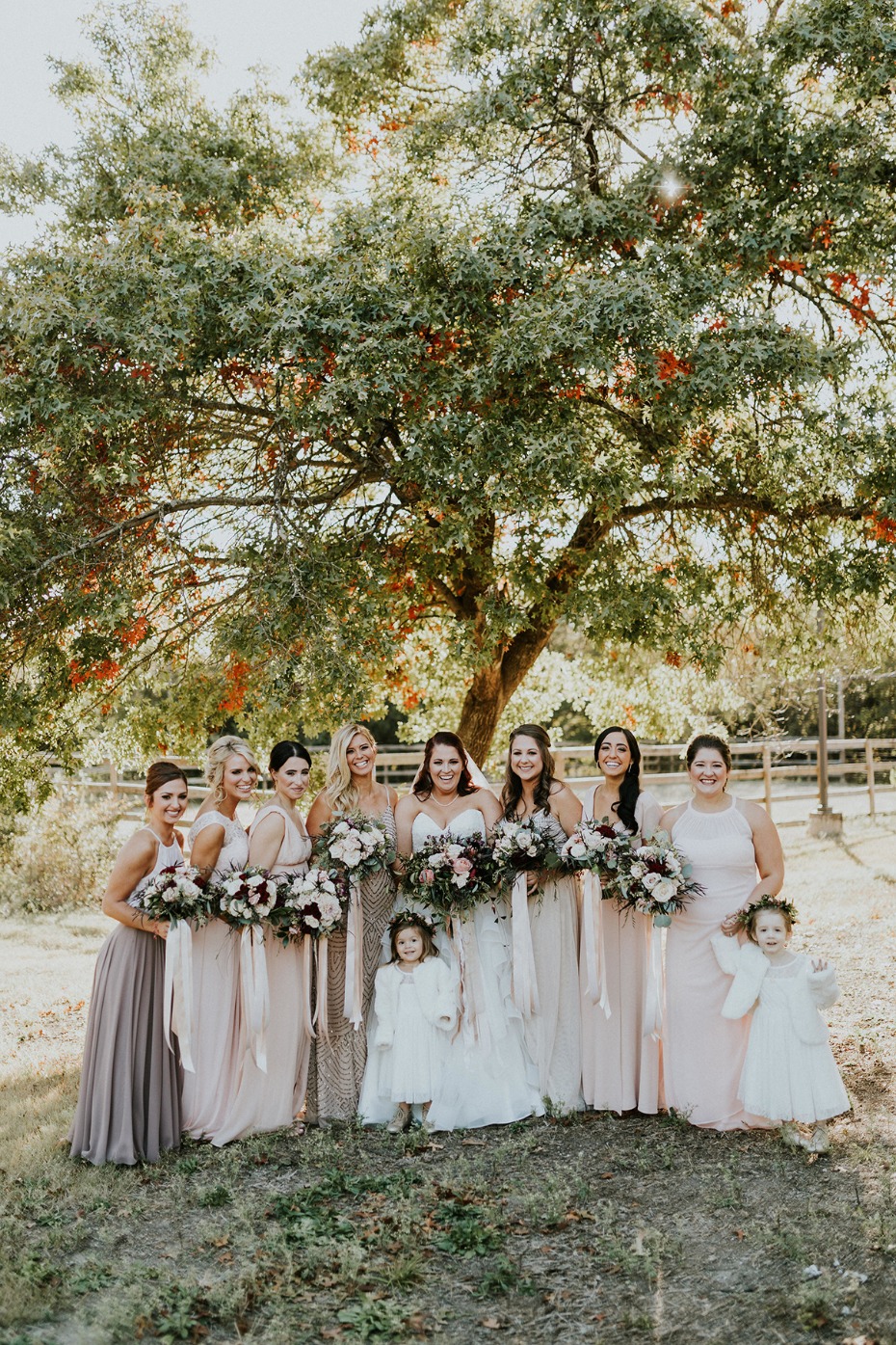 Bride with bridesmaids in blush dresses at outdoor wedding