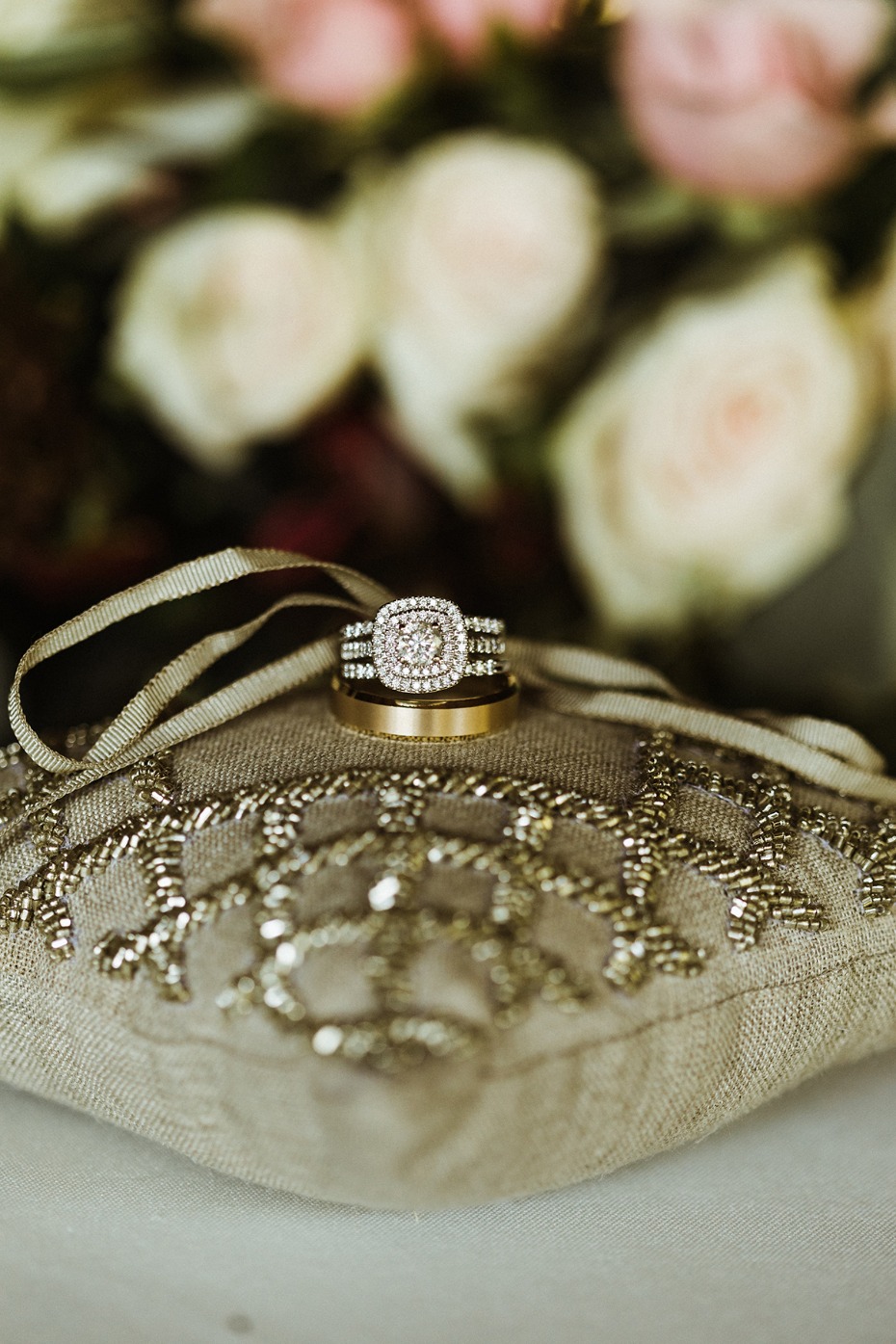 Wedding rings on a decorative pillow with floral background