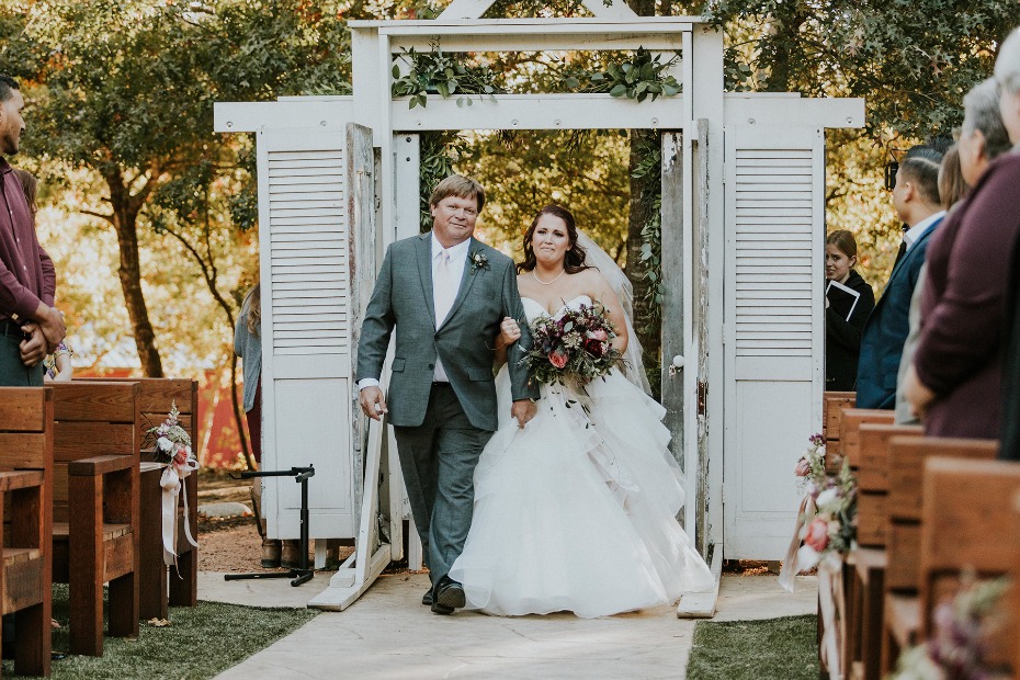 Bride and father walk down aisle at outdoor wedding