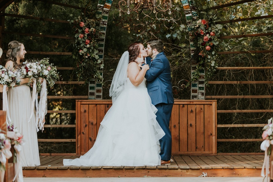 Newlyweds share a kiss at their outdoor wedding ceremony