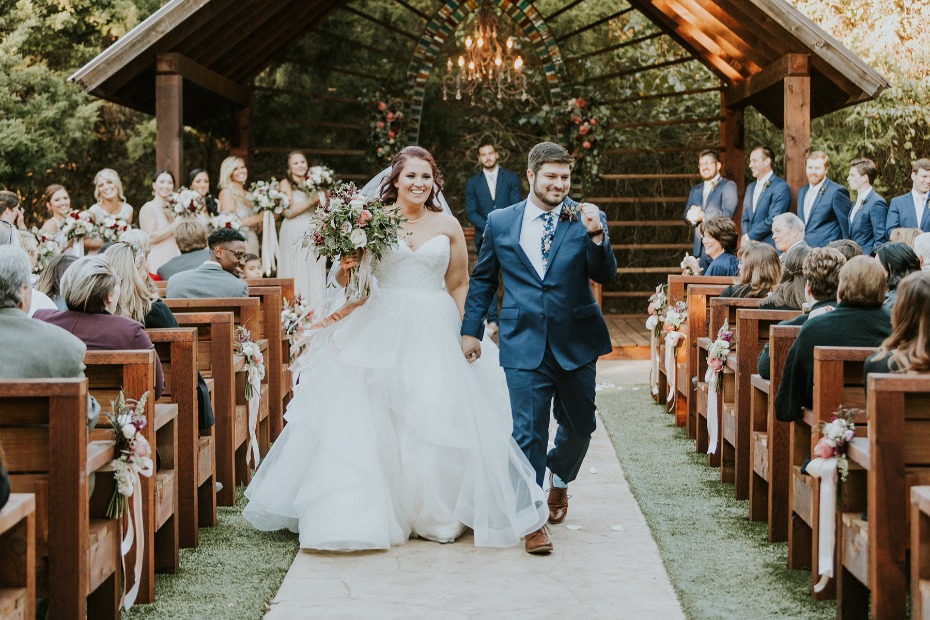 Bride and groom happily walking down wedding aisle