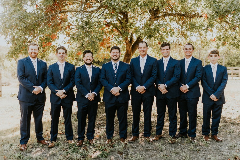 Groomsmen in navy suits at an outdoor wedding event