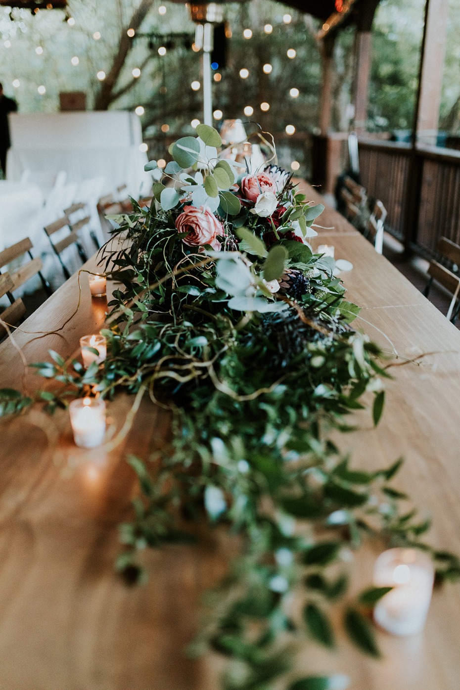 Wedding table centerpiece with lush greenery and candles