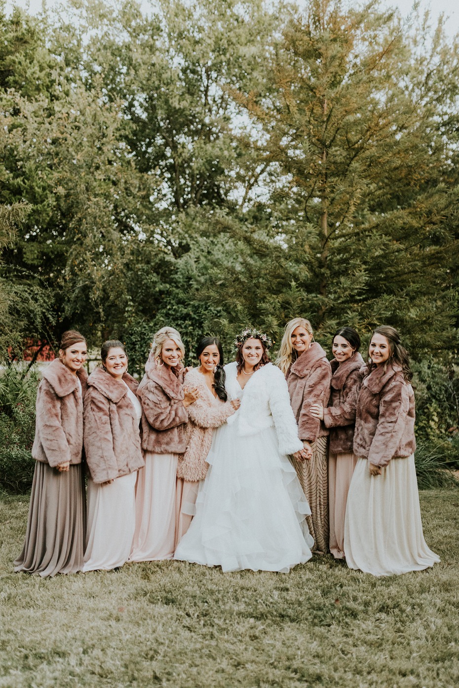 Bride and bridesmaids in fur coats at outdoor wedding