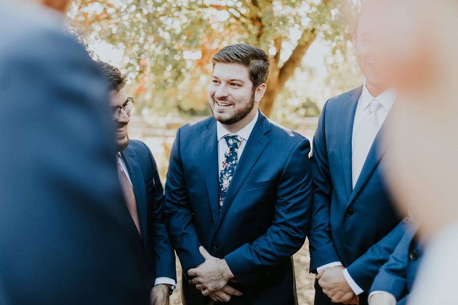 Groomsmen in navy suits outdoors smiling at wedding