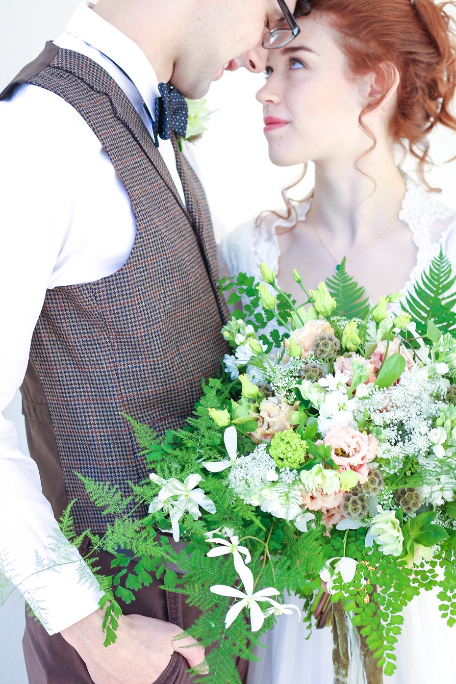 Bride and groom forehead to forehead with floral bouquet