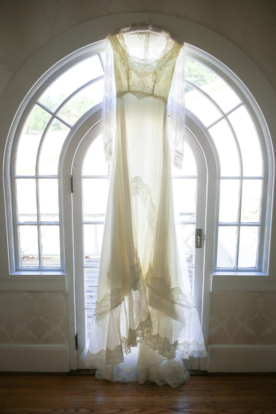 Vintage lace wedding dress hangs in arched doorway
