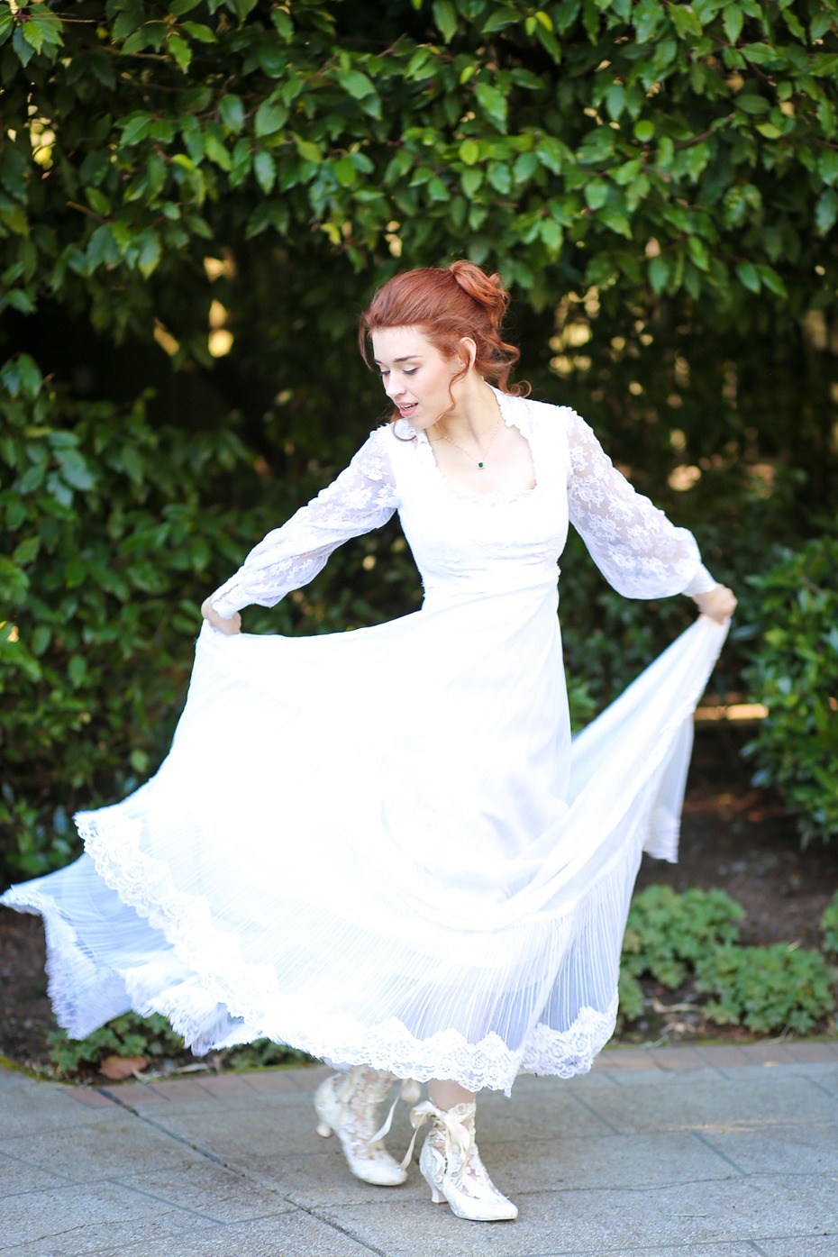 Redhead woman twirling in a vintage white lace dress