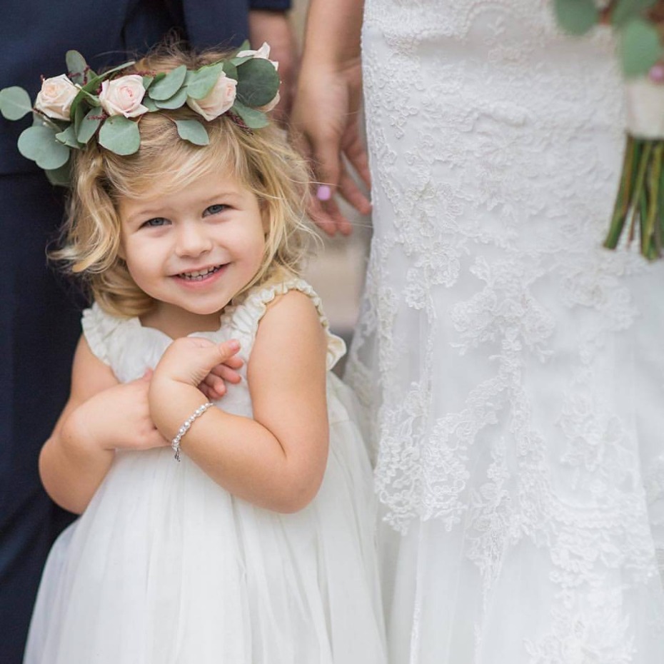 Adorable flower girl in white dress and floral crown