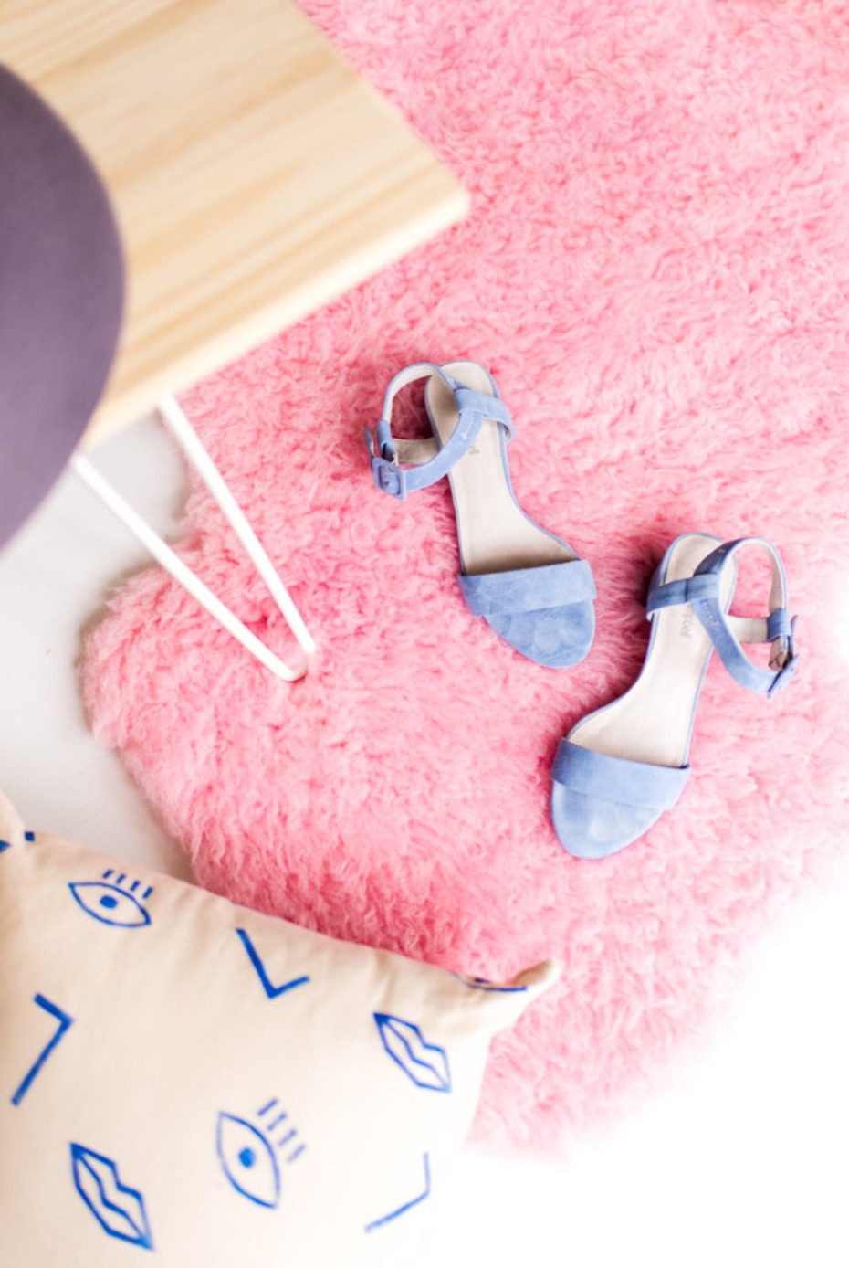 Blue heels on a pink rug next to a patterned pillow