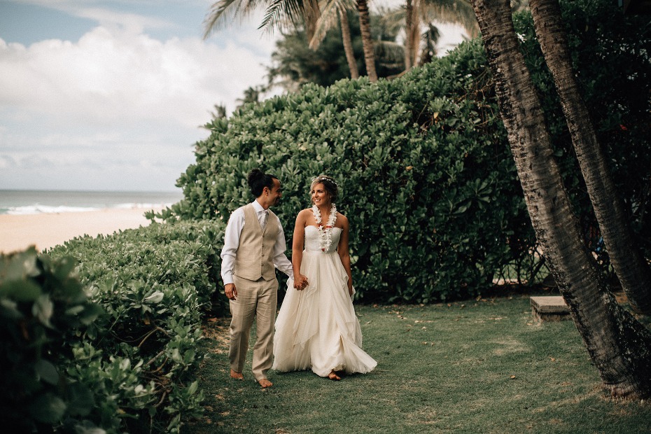 Barefoot couple walking by the beach after their wedding