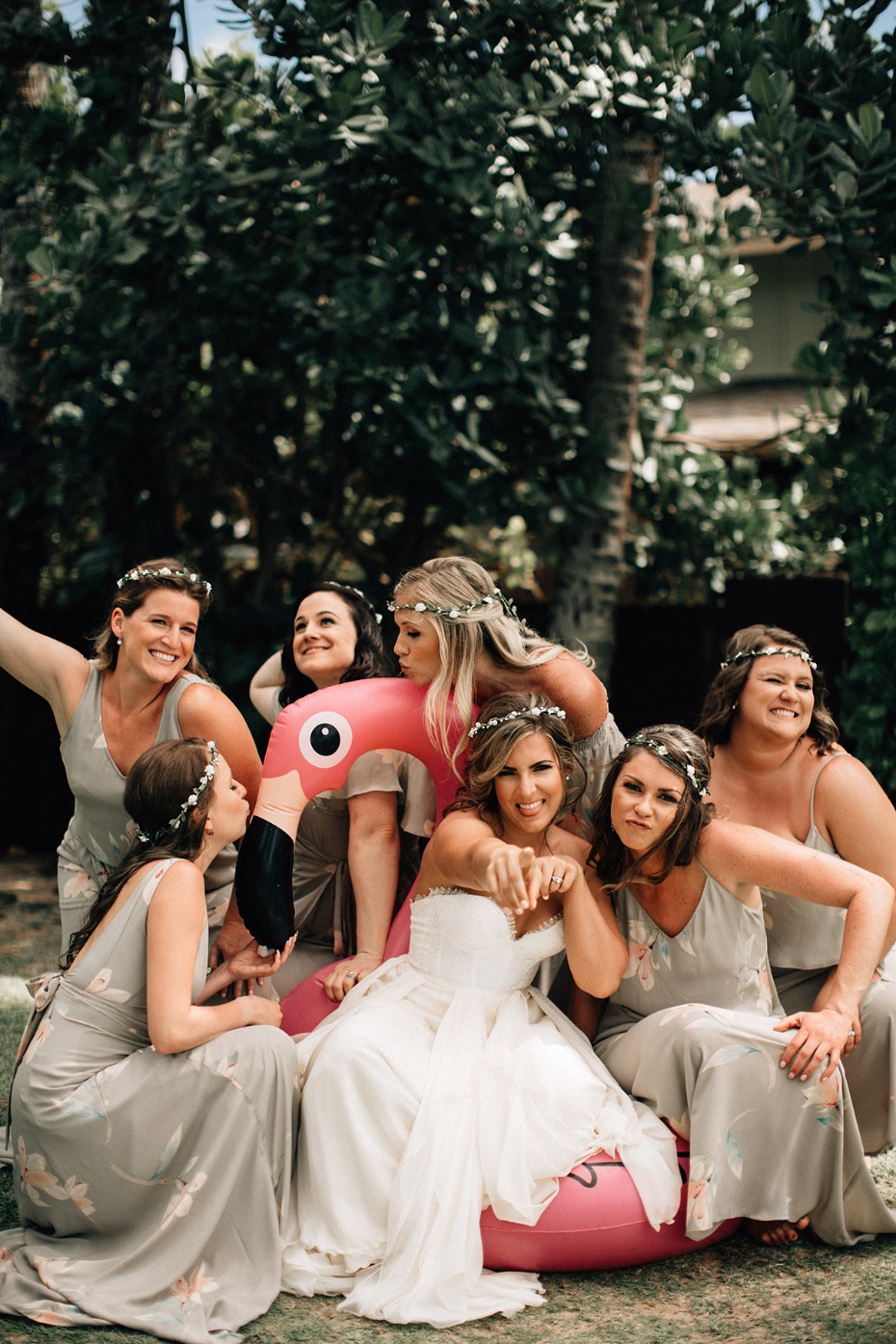 Bride and bridesmaids pose with a pink flamingo float