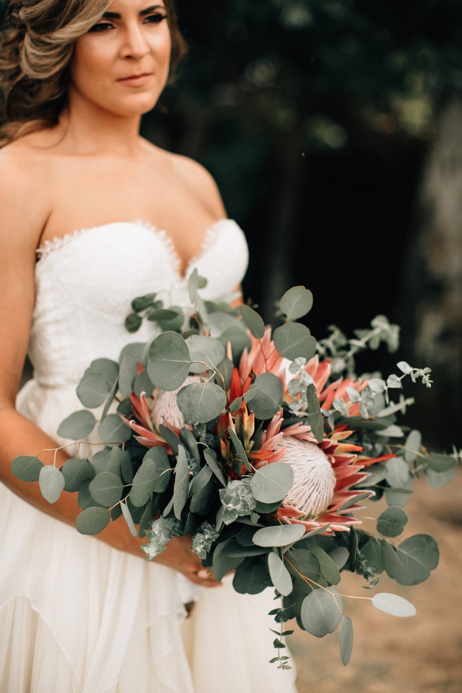 Bride holds king protea and eucalyptus wedding bouquet