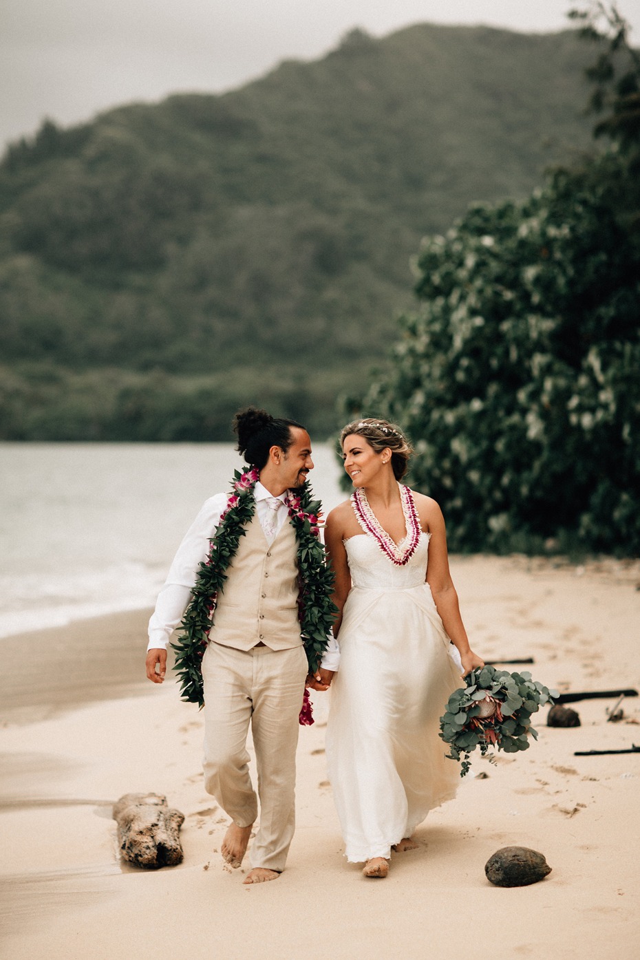 Happy couple barefoot on a beach after wedding ceremony