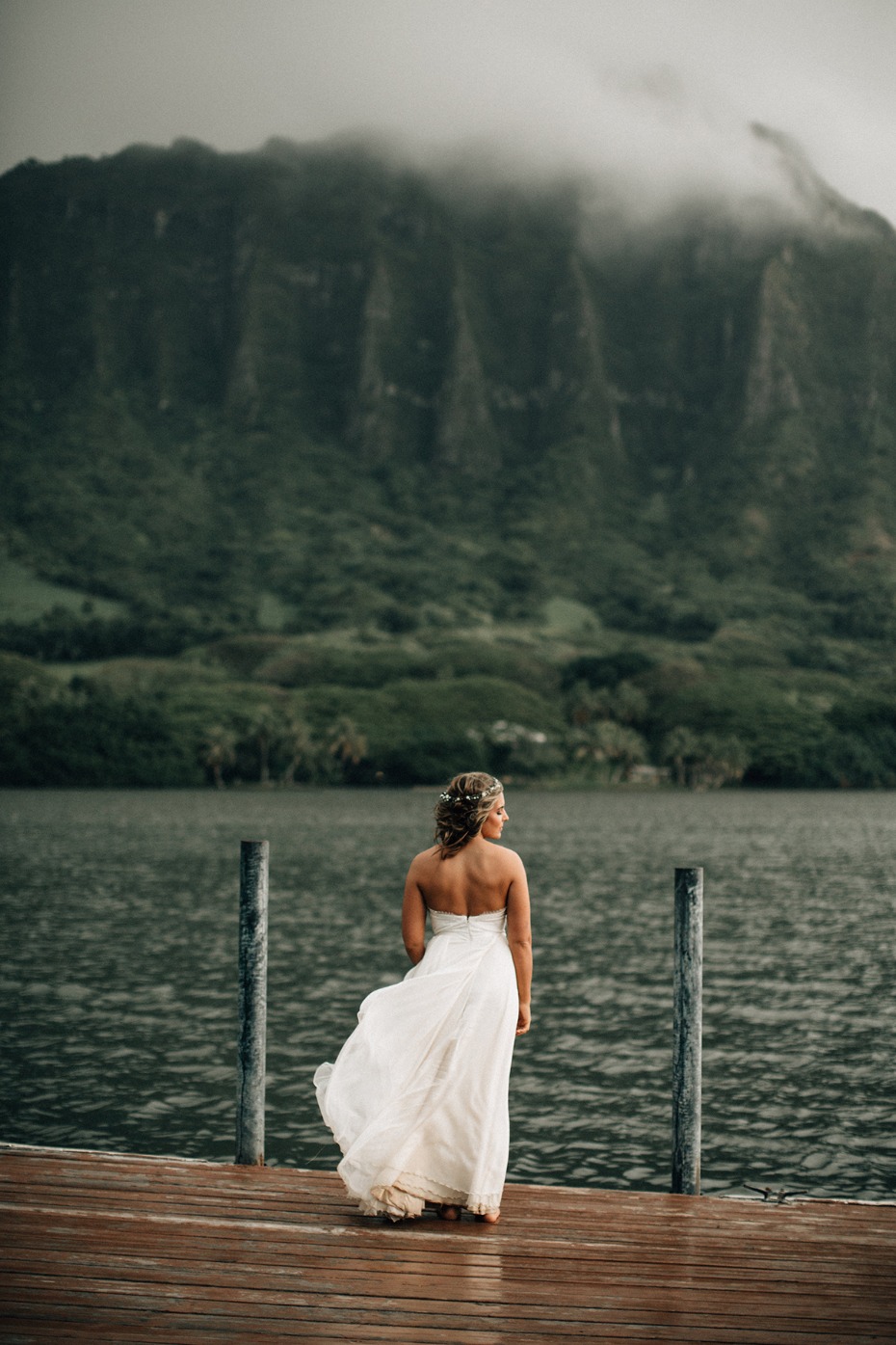 Bride gazes at misty mountains in flowing white dress