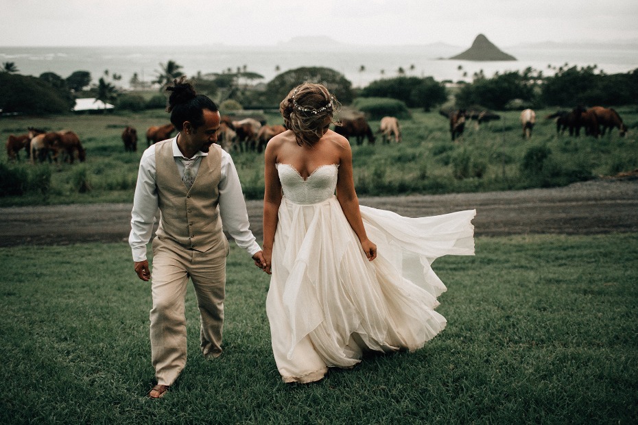 Bride and groom walk handinhand on rural Hawaii farm
