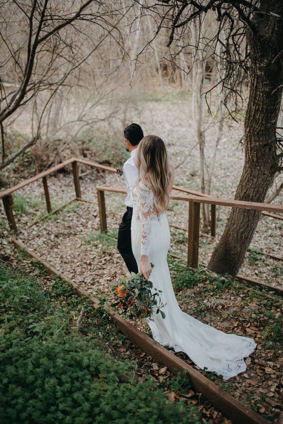 Bride and groom walking down wooden steps in nature