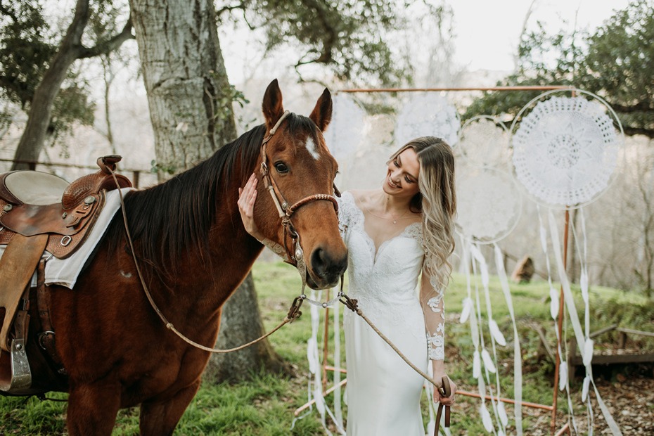 Bride in white dress with her horse on wedding day