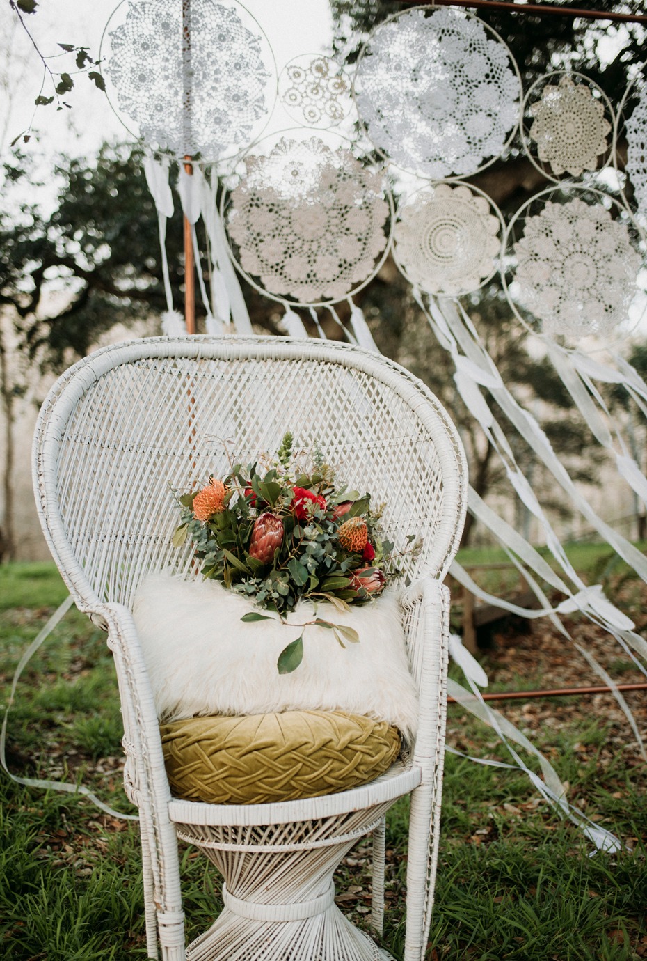 Boho chic wicker chair with floral bouquet and dream catchers